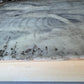 Marble-like surface with swirling patterns and speckles on a wooden base