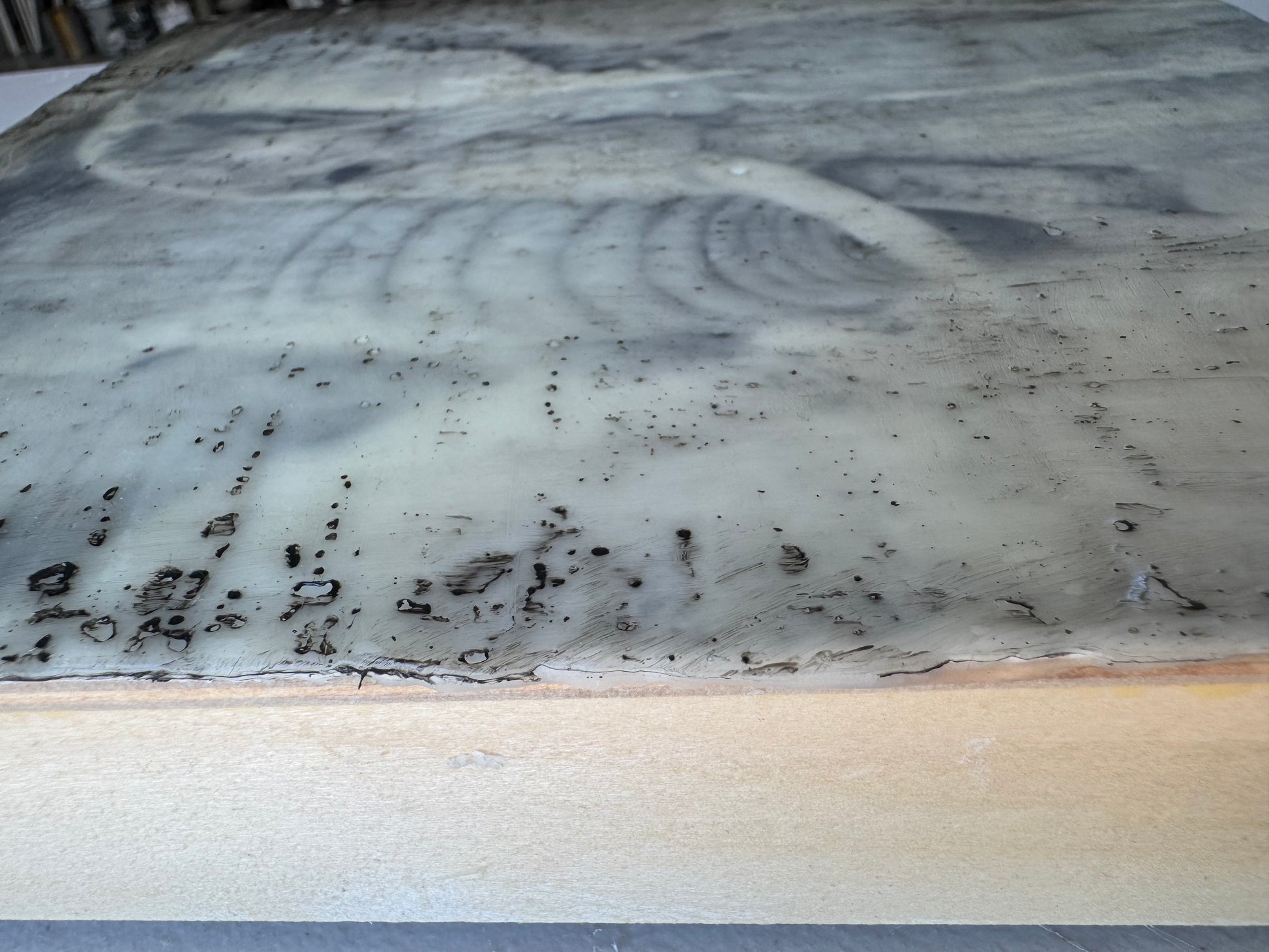 Marble-like surface with swirling patterns and speckles on a wooden base
